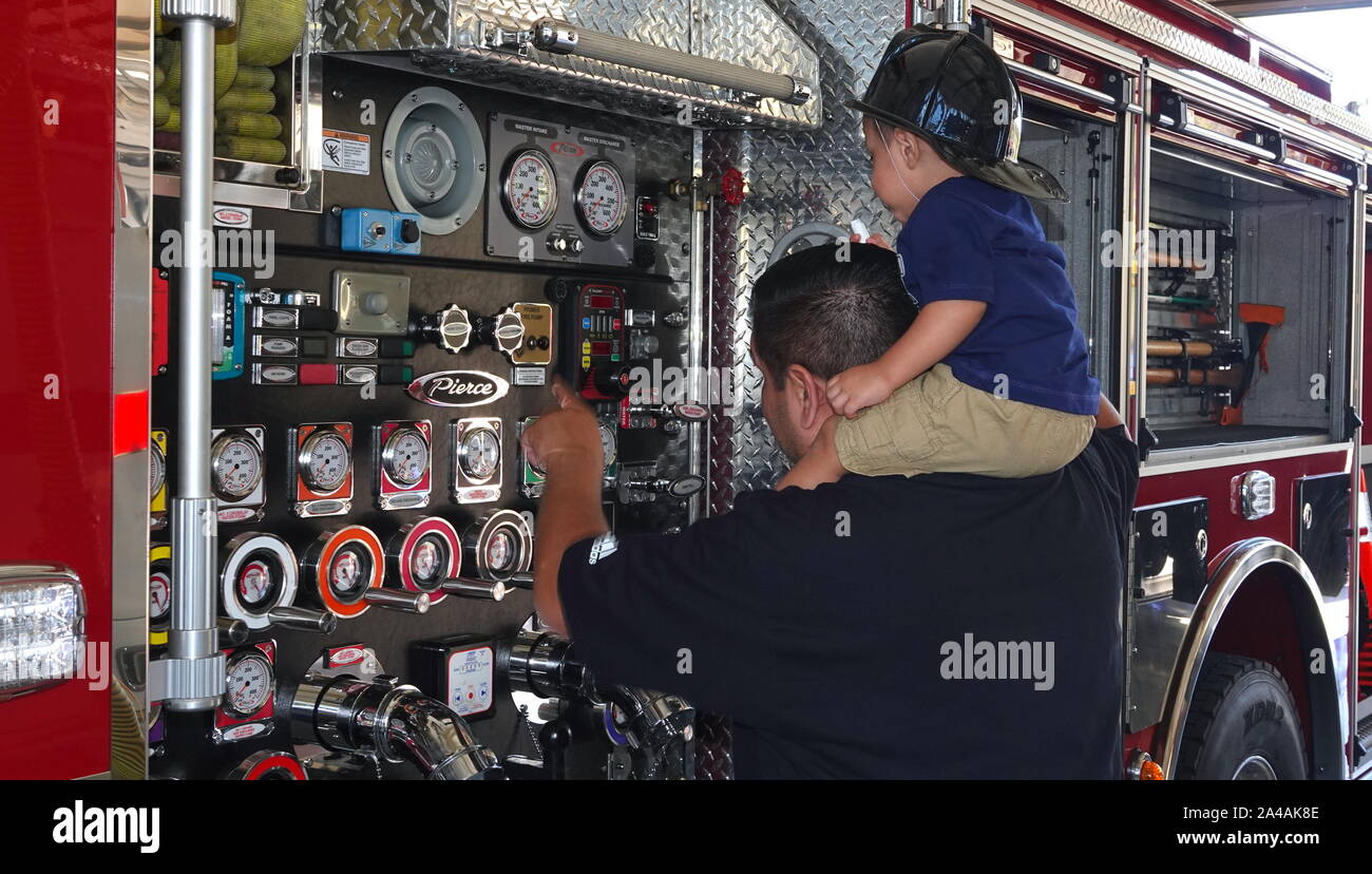 Un père montre à ses fils l'enfant sur les mesureurs d'un camion d'incendie sur l'affichage à la station d'incendie portes ouvertes. Banque D'Images