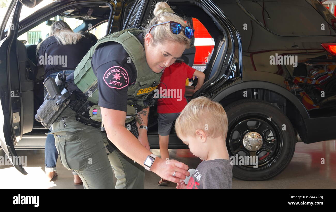 Une femme agent de police donne un petit garçon un autocollant à fire station ouverte chambre. Banque D'Images