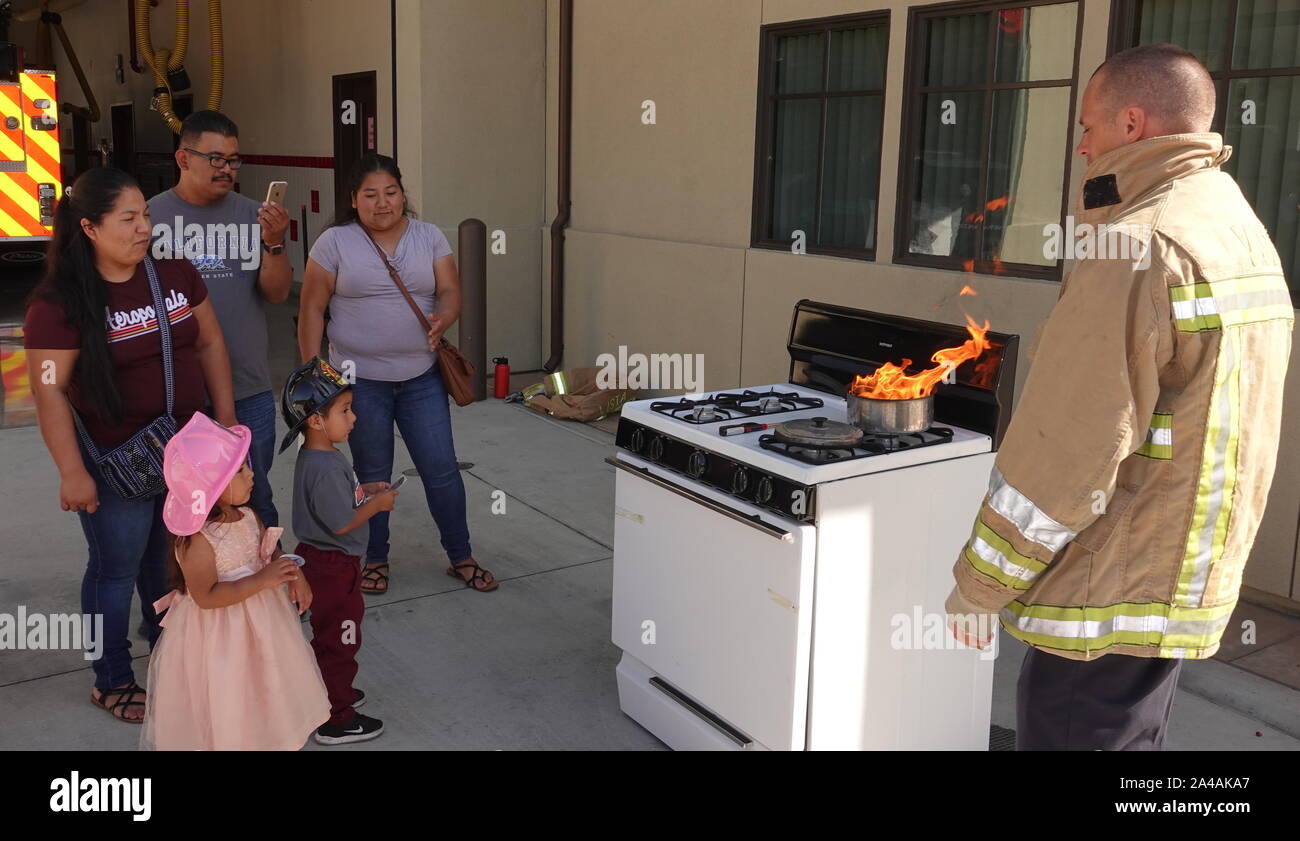 Un pompier d'une famille hispanique démontre comment pout hors ménage commun au feu fire station ouverte chambre. Banque D'Images