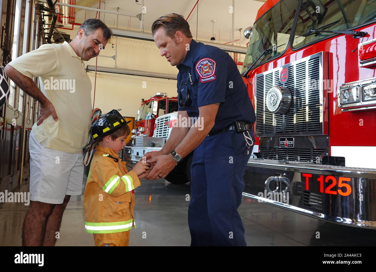 Un petit garçon habillé en pompier peut rencontrer son idole à fire station ouverte chambre Banque D'Images