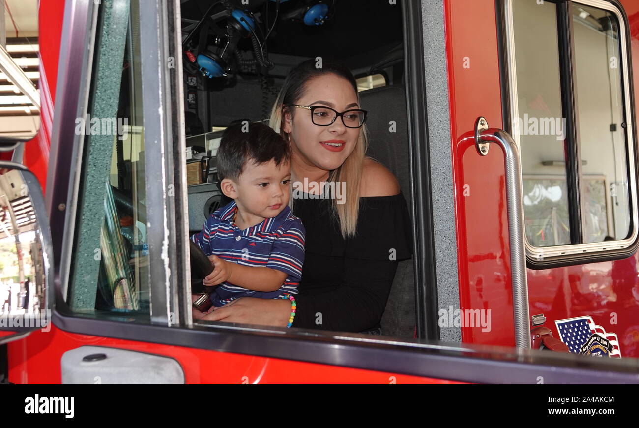 Une jeune mère hispanique et son petit garçon s'asseoir dans un camion d'incendie au cours de la station d'incendie portes ouvertes. Banque D'Images