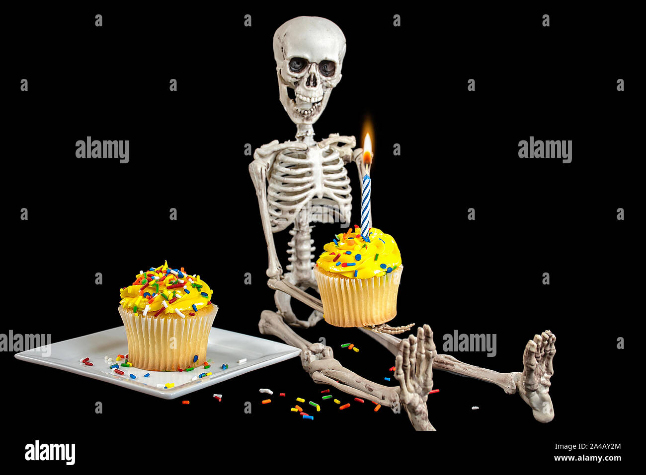 La tenue d'un squelette birthday cupcake with candle isolated on black Banque D'Images