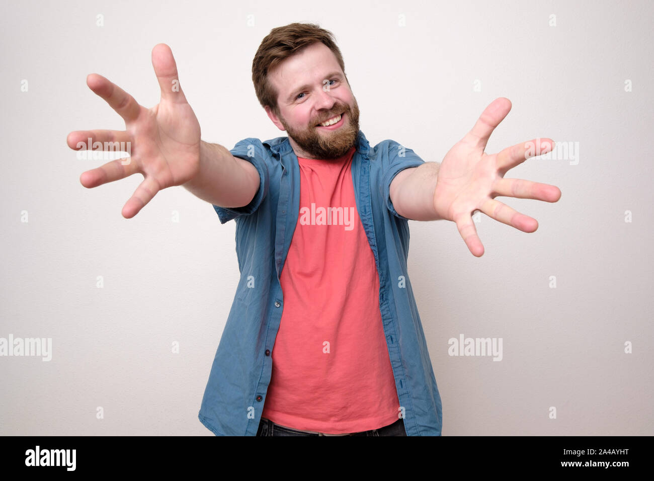 Un bon caractère barbu tire ses mains à l'appareil photo et veut caresser, sourire accueillant un(e) ami(e). Isolé sur fond blanc. Close-u Banque D'Images