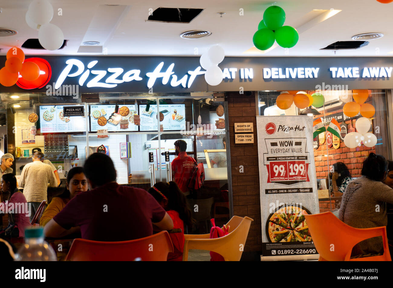 Foule de gens assis à l'extérieur d'un magasin de Pizza Hut en Inde Asie Banque D'Images