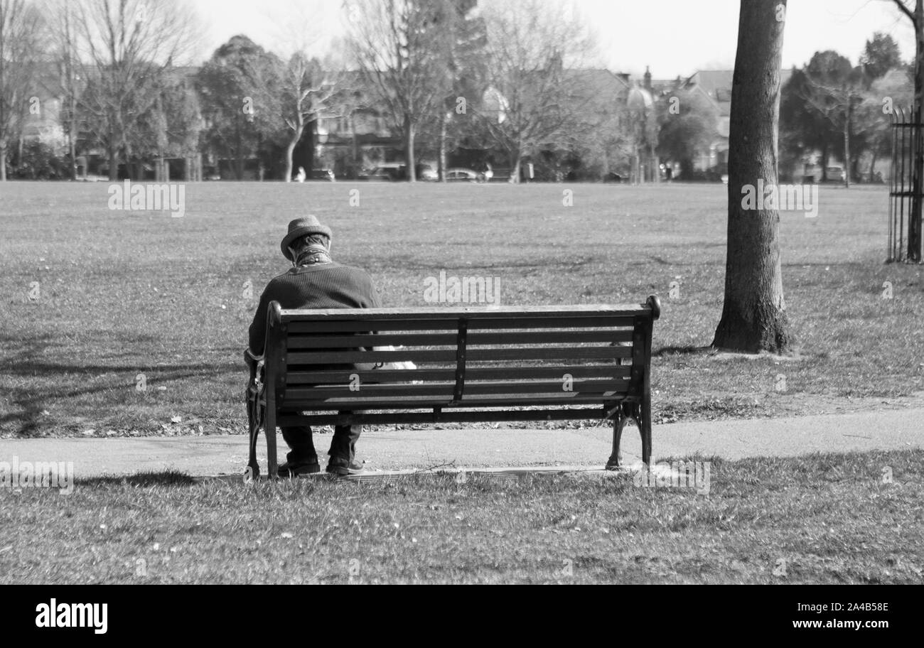 Un vieil homme est assis sur un banc de la lecture Photo Stock - Alamy