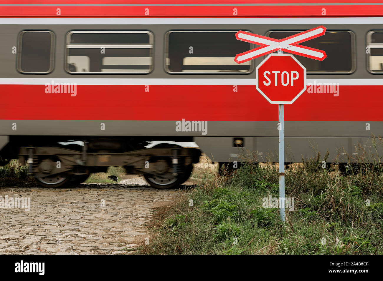 St Andrew's Cross et panneau d'arrêt au passage à niveau de chemin de fer et la jonction de route pavée de pays avec le train sur les rails Banque D'Images