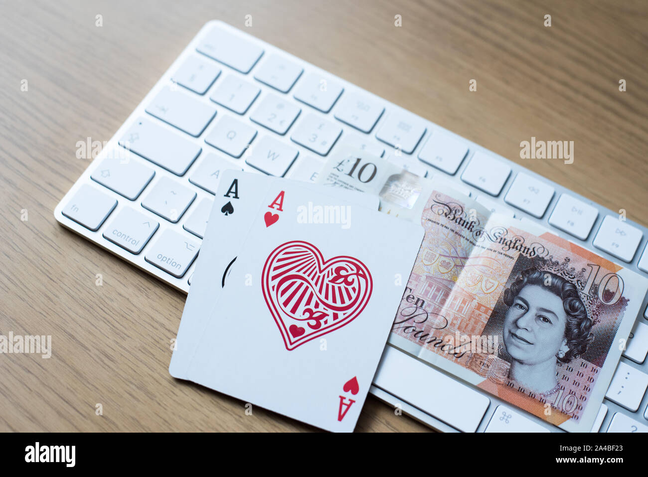 En ligne le jeu de poker et jouer avec le clavier sur un tableau avec double as et un dix livres britanniques en polymère Banque D'Images