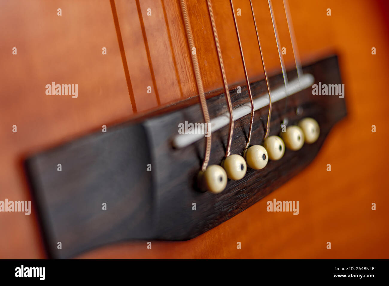 String d'une guitare acoustique à l'avant-plan de la chaîne, avec le collier de fixation des axes pont Banque D'Images