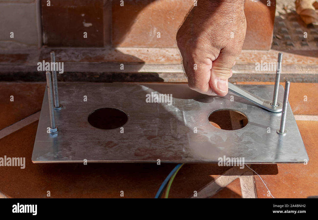 Mains d'un homme qui sont le serrage d'un écrou avec une clé fixe sur une plaque d'ancrage en métal d'un moteur électrique Banque D'Images