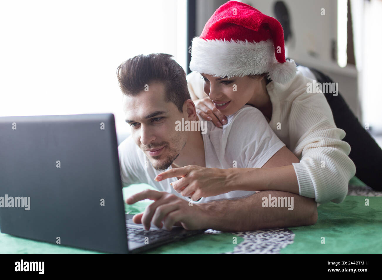 Jeune couple magasinage en ligne sur ordinateur portable pour Noël à la maison, le choix de produit Banque D'Images