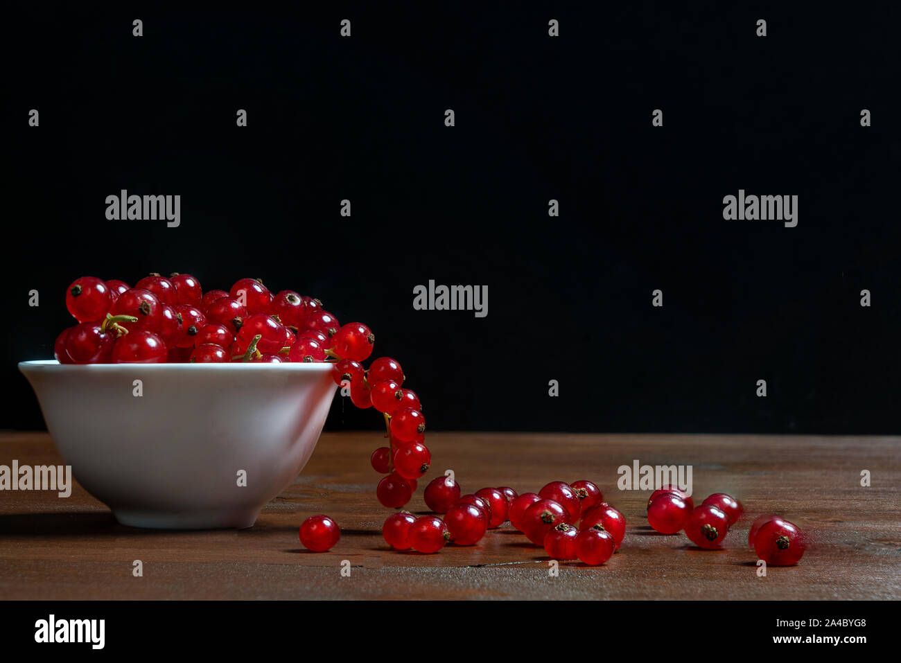 Un bol blanc de cassis avec quelques fruits sur une surface en bois Banque D'Images