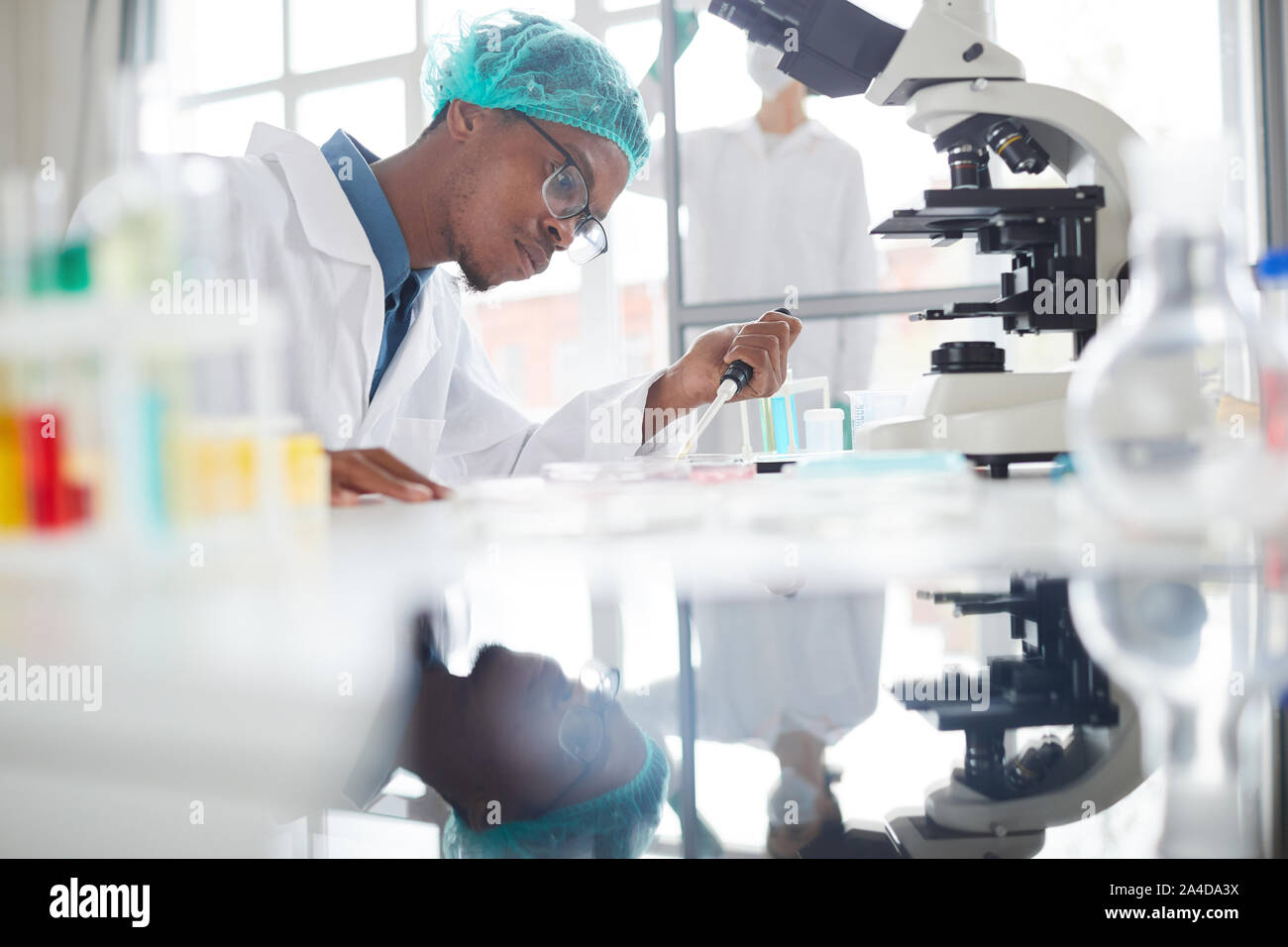 Vue de côté portrait de l'homme afro-américain travaillant dans la préparation d'échantillons de laboratoire de test dans la boîte de Pétri pour la recherche médicale, copy space Banque D'Images