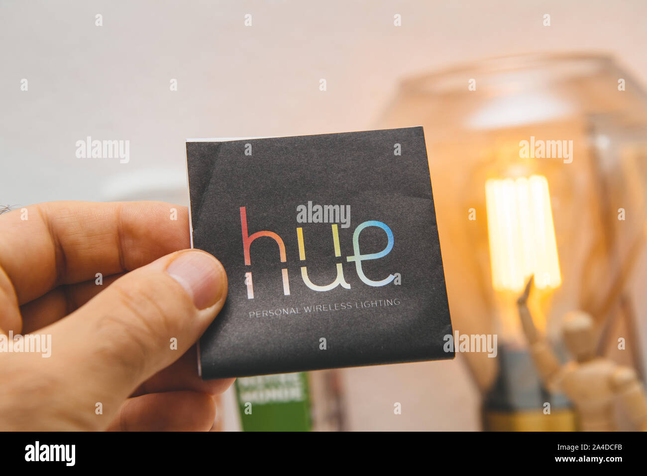 Paris, France - Sep 13, 2019 : Man hand holding Hue Philips éclairage sans fil personnel notice pour l'appareil avec le filament de lumière LED allumé à l'arrière-plan Banque D'Images