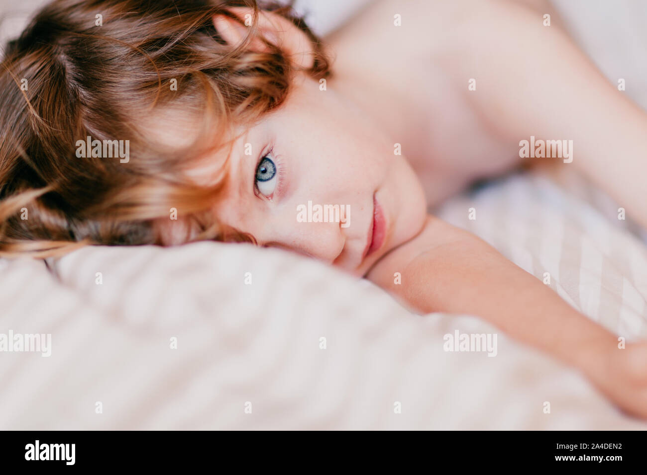 Portrait d'un garçon allongé sur un lit Banque D'Images