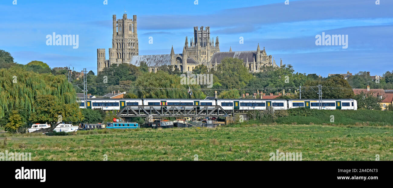 East Anglia vue panoramique paysage Marais bateaux amarrés sur la rivière Great Ouse ci-dessous pont de chemin de fer train arrive Ely toile Station Cathédrale d'Ely en Angleterre UK Banque D'Images
