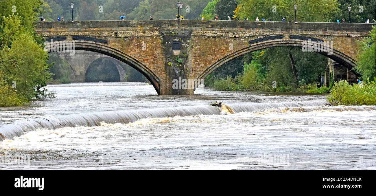 Les gens qui marchent sur l'arch Framwellgate Bridge par temps humide River porter des éventuelles inondations après de fortes pluies de l'été à Durham England UK Banque D'Images
