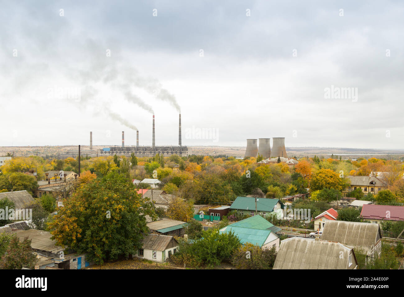 Station d'énergie thermique avec bâtiments résidentiels à l'avant-plan. Les cheminées et les tours de refroidissement. Ciel nuageux gris, jaunissement des arbres d'automne Banque D'Images