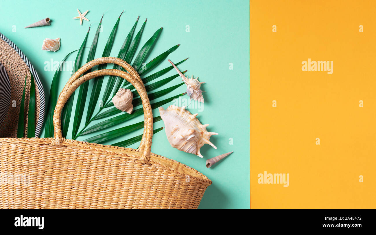 Mode d'été mises à plat. Sac de paille élégant, hat, feuilles de palmier, des coquillages sur fond vert et jaune à la mode. Vue d'en haut. Copier l'espace. Lifestyl durable Banque D'Images