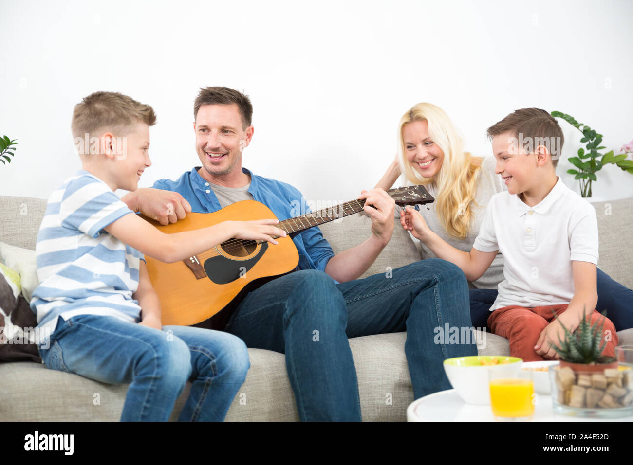 Happy caucasian family smiling, jouer de la guitare et chanter des chansons ensemble au confortable moderne accueil Banque D'Images