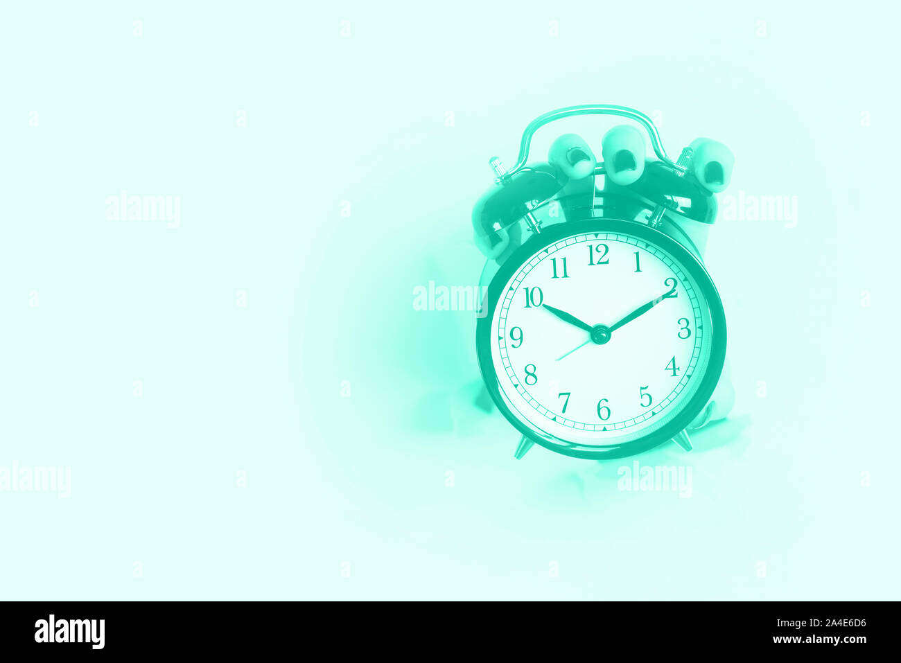 Réveil noir tenir la main à travers le trou dans l'arrière-plan couleur menthe. Service de concept d'alerte. Couleur turquoise et vert à la mode. La routine du matin. Banner Banque D'Images