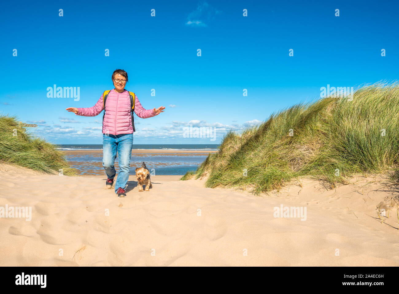 Femme sud-coréenne avec chien sur des dunes de sable où Norfolk Coast PATH National Trail de Burnham Overy Staithe atteint la mer, East Anglia, Angleterre, Royaume-Uni Banque D'Images