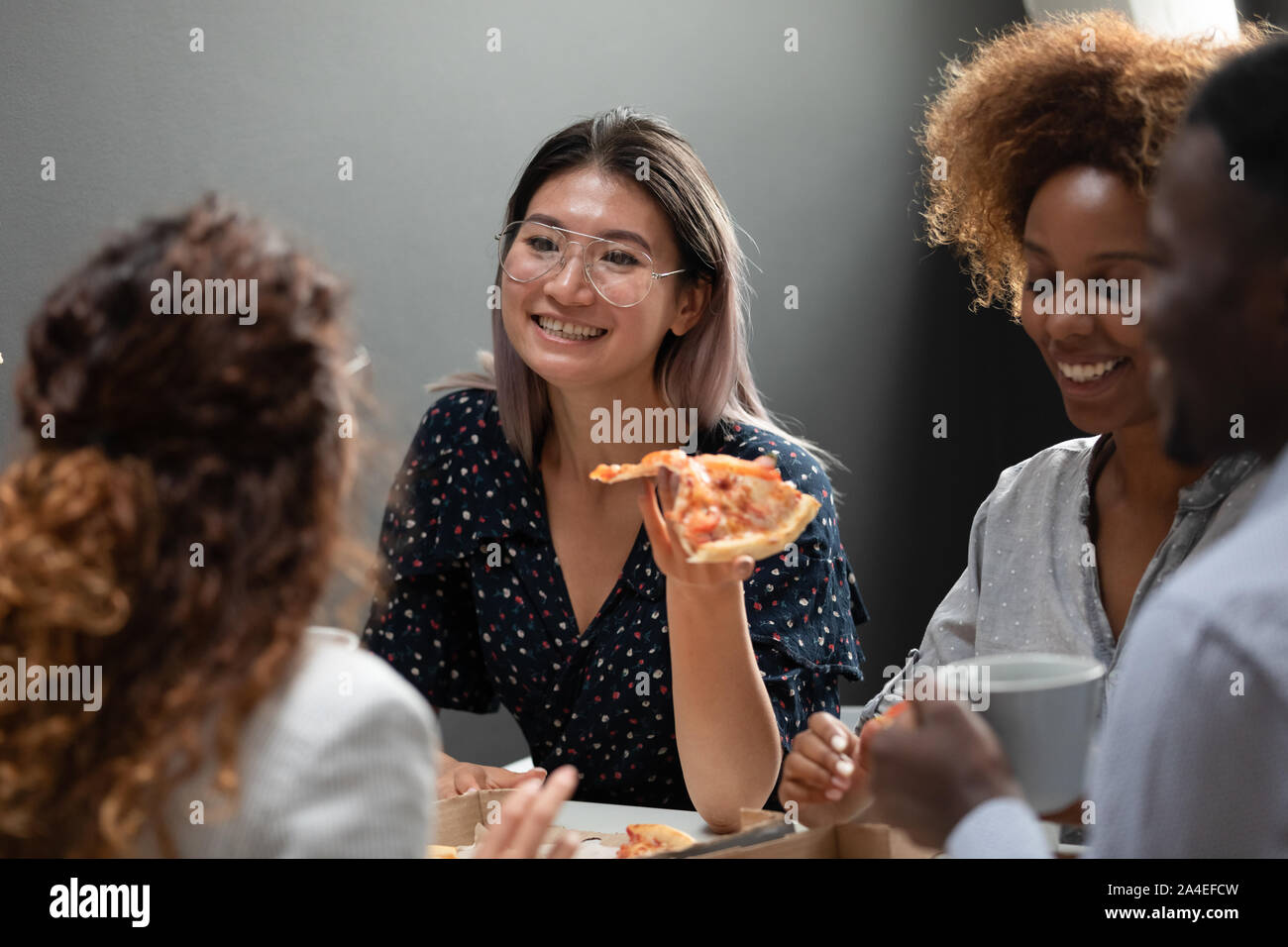 Employé de bureau asiatique manger une pizza avec des collègues Banque D'Images