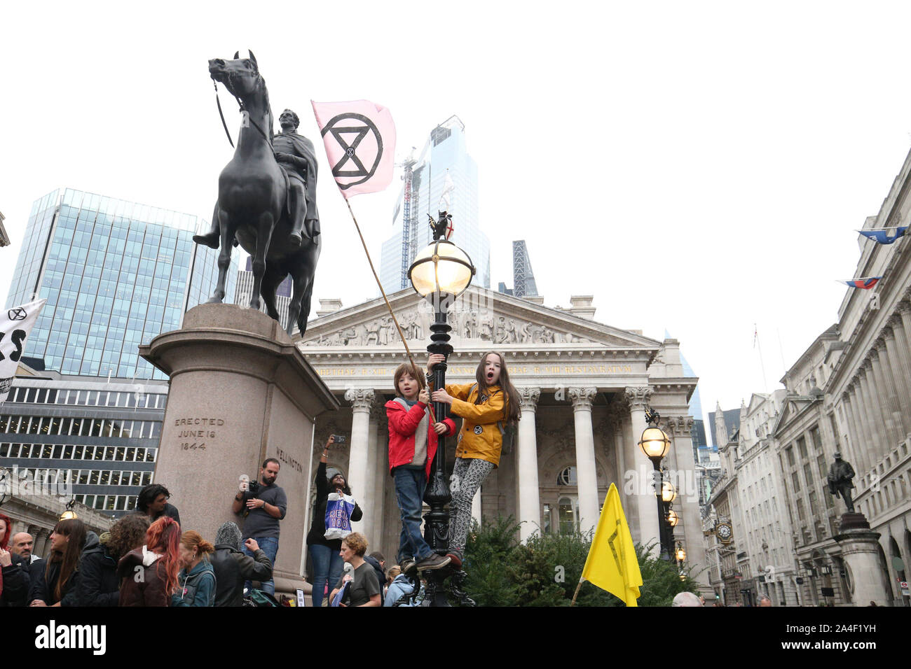 Jeunes manifestants debout sur un lampadaire, à droite de la statue du duc de Wellington, en face de la Royal Exchange, Londres, au cours d'une rébellion d'Extinction (XR) changement climatique de protestation. Banque D'Images