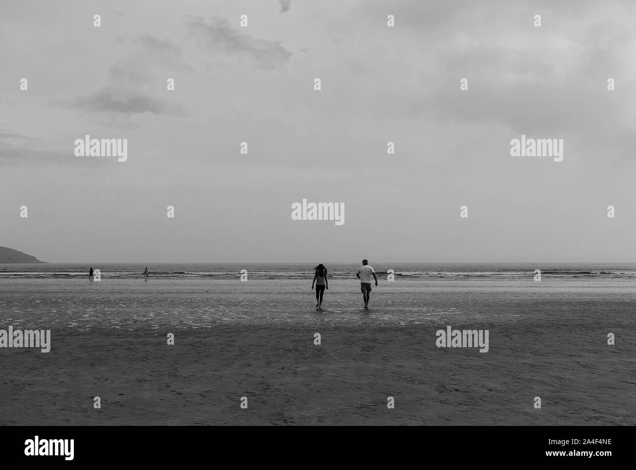 Couple en train de marcher sur une plage de sable en laissant des traces de pas dans le sable. Un père et sa fille profiter de la journée. Jour nuageux. Banque D'Images