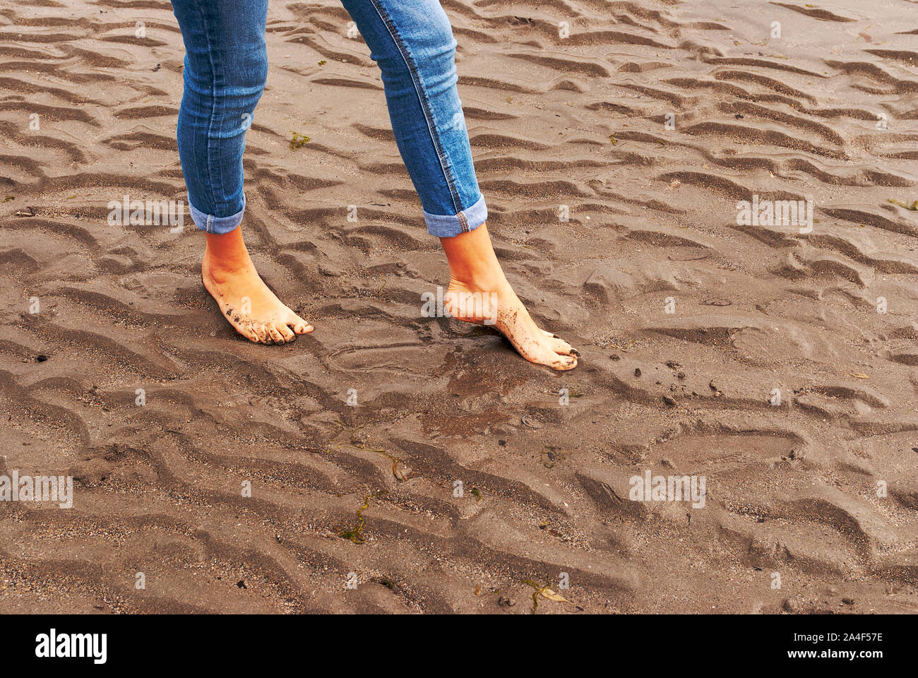 Jeune femme marcher et jouer sur une plage de sable et laissant des traces de pas dans la plage. Killbrittain, Kilbrittain beach, en Irlande. Banque D'Images