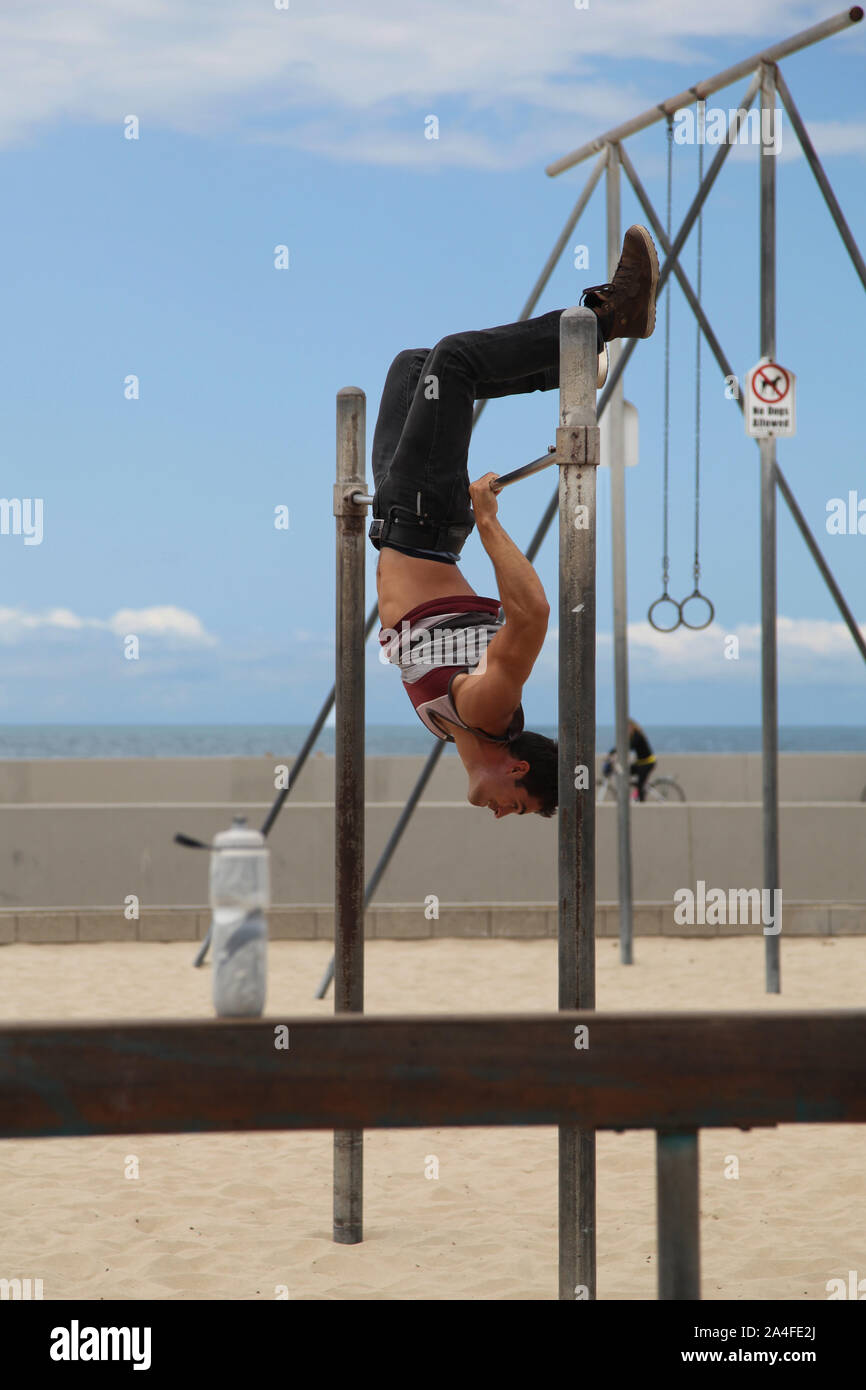 Venice Beach, Californie - un gymnaste masculin dans la poignée sur les barres, exercice public sur la plage de Venice Banque D'Images