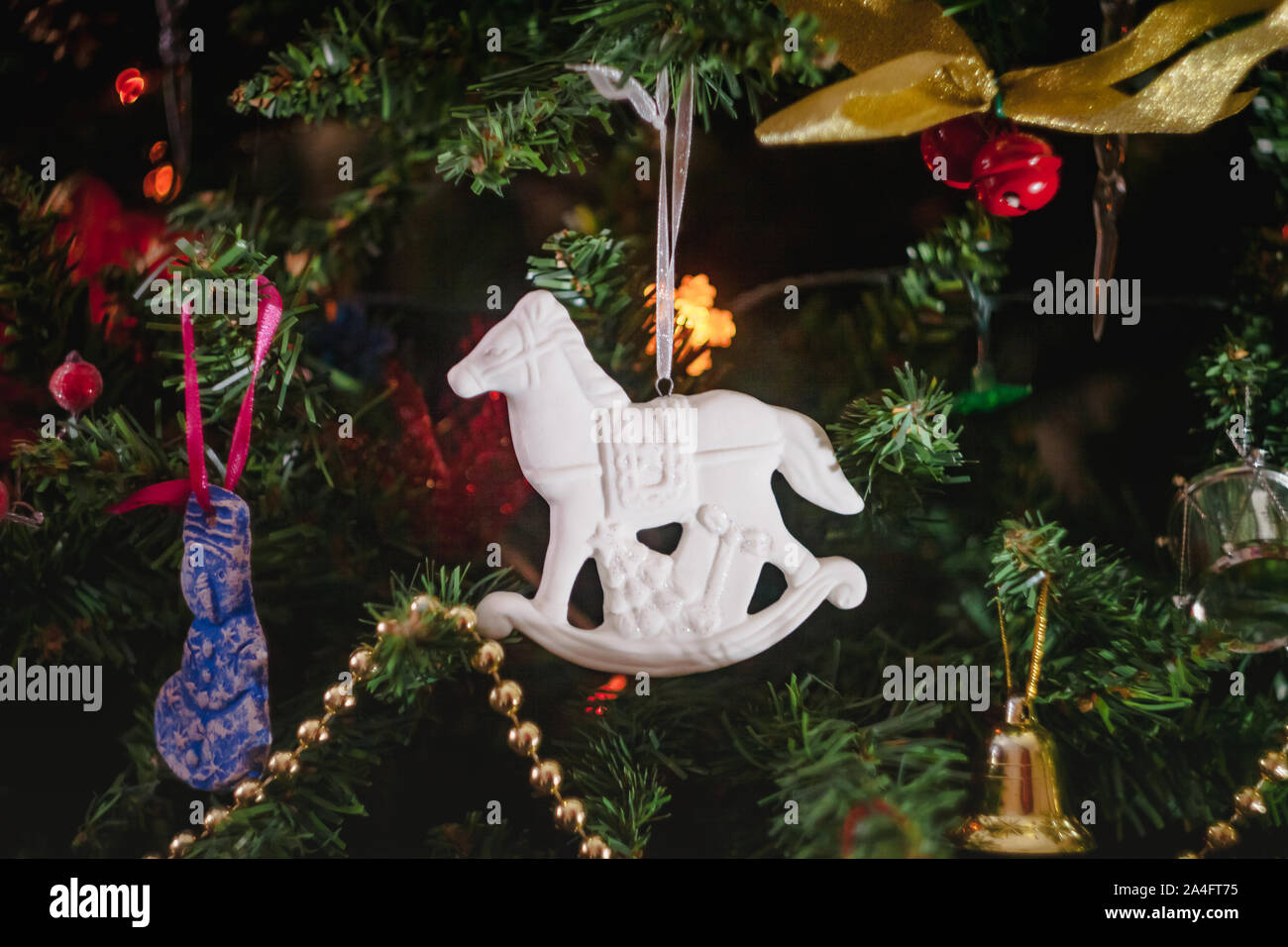 Les jouets de Noël sous la forme d'un mobilier ancien en céramique blanche avec des cadeaux cheval à bascule sur un arbre de Noël décoré. Close-up. Banque D'Images