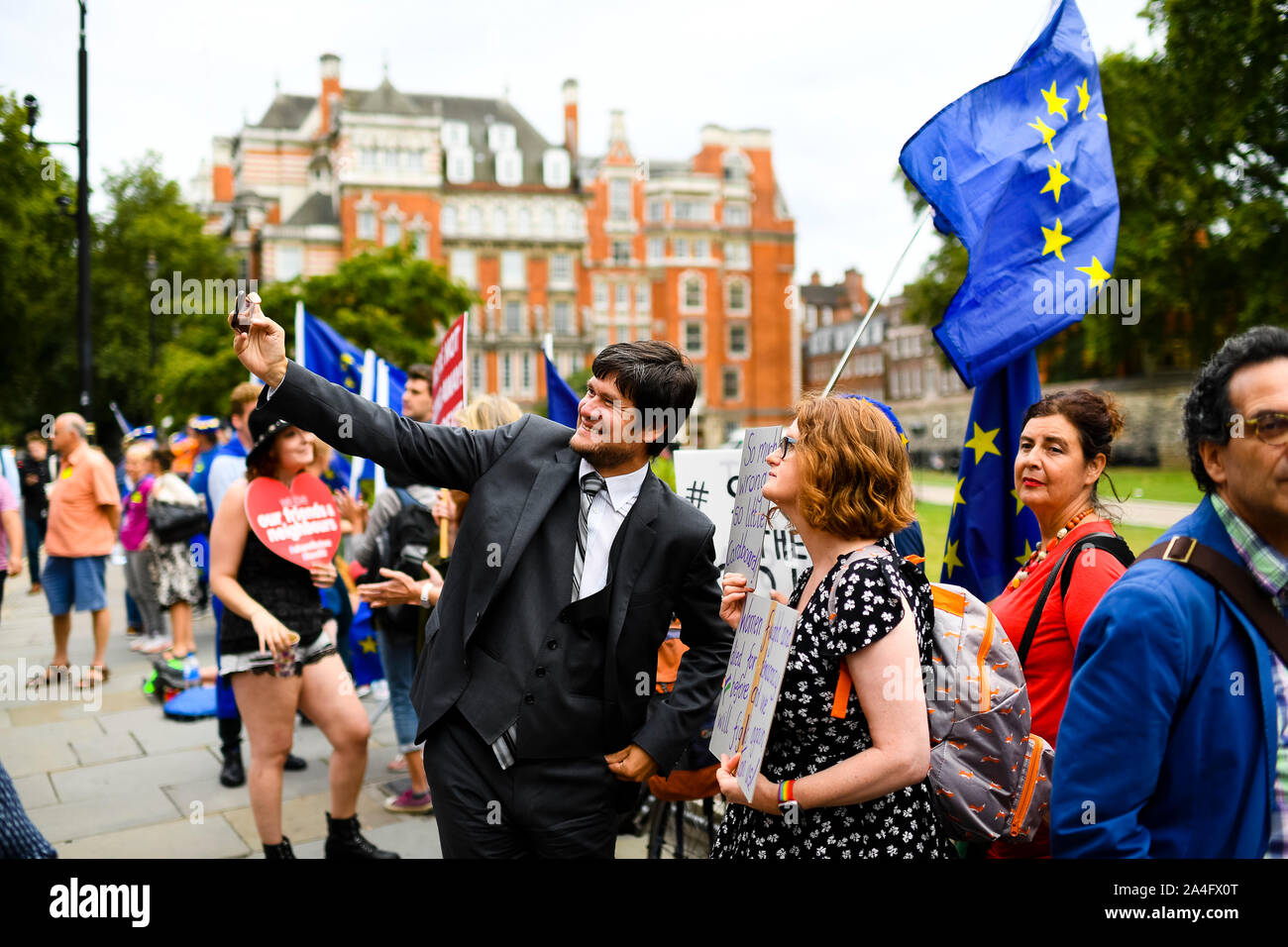 Londres, Royaume-Uni. Un passant prend un pro-selfies avec manifestants restent en face du Palais de Westminster. Banque D'Images