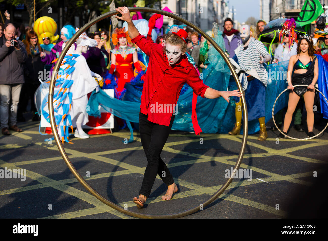 Londres, Royaume-Uni. Un artiste interprète ou exécutant avec un cerceau géant danse au milieu d'un carrefour au cours de l'extinction La rébellion protester sur Oxford Street. Banque D'Images