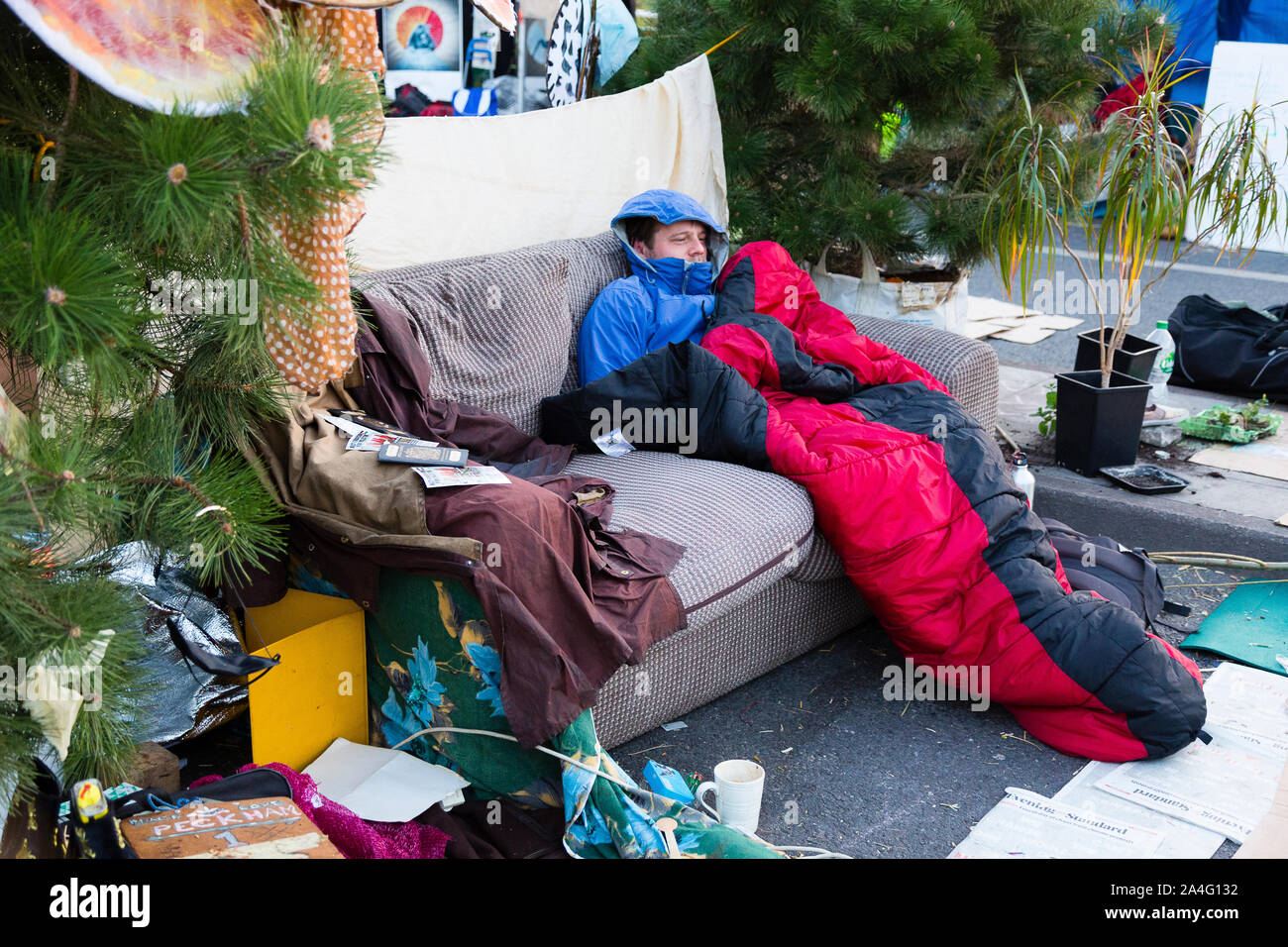 Londres, Royaume-Uni. Un homme enveloppé dans un sac de couchage est assis sur un canapé au milieu de Waterloo Bridge sur cinq jours de la rébellion des manifestations à Londres d'Extinction Banque D'Images