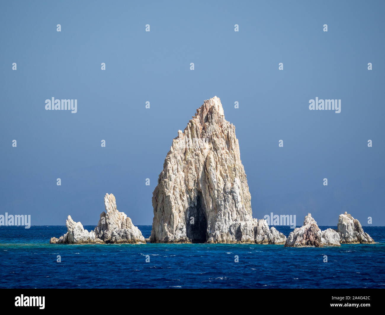 Une vue de Poliegos jaggered aiguilles sharp dents roches Péloponnèse, Grèce dans le calme de l'eau de mer sous ciel bleu clair Banque D'Images