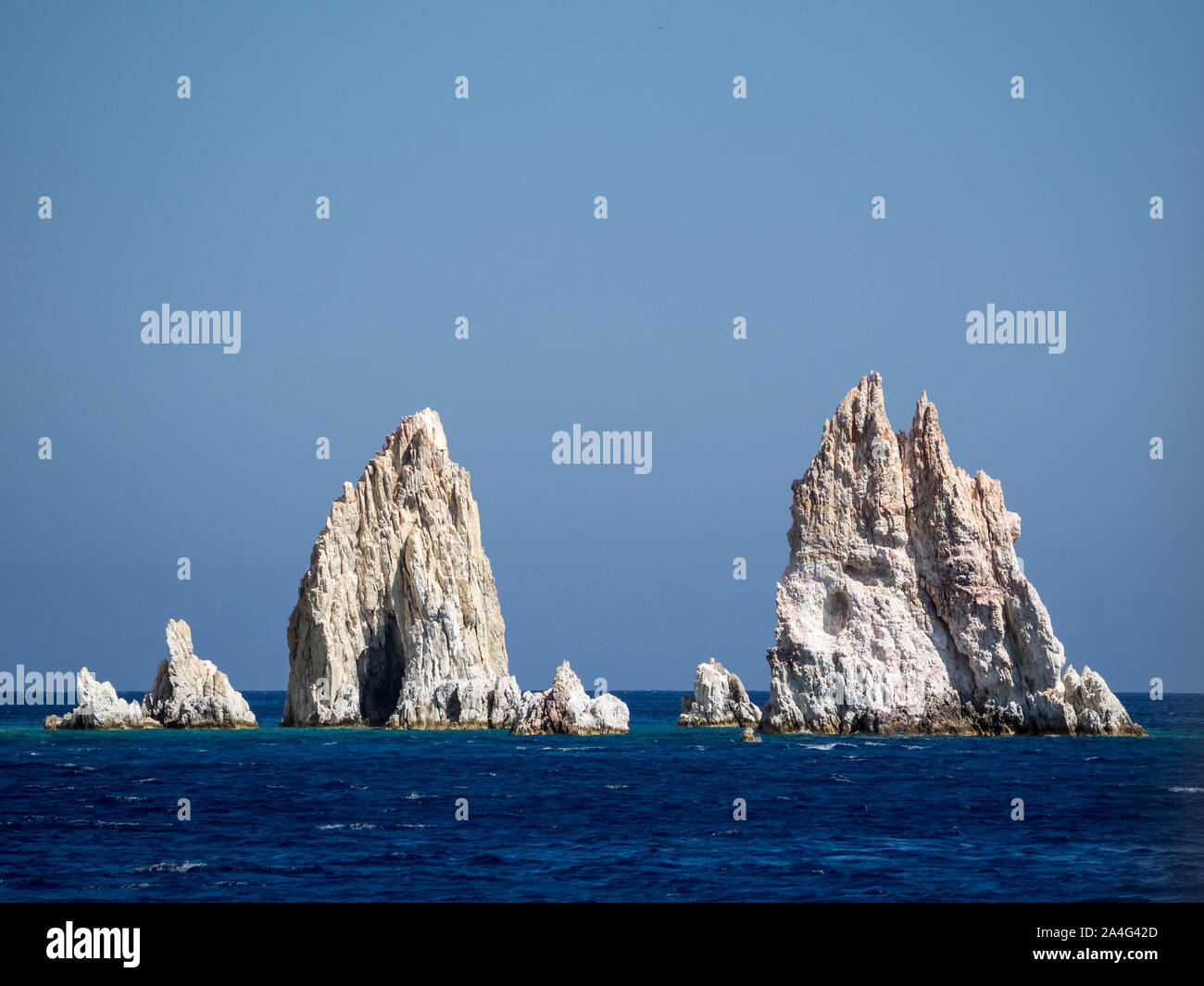 Une vue de Poliegos jaggered aiguilles sharp dents roches Péloponnèse, Grèce dans le calme de l'eau de mer sous ciel bleu clair Banque D'Images