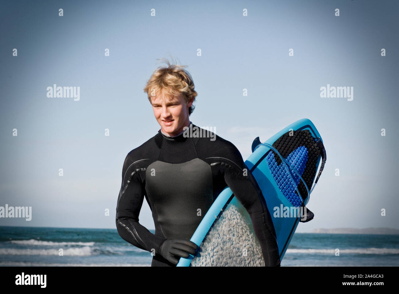 Jeune homme portant une combinaison isothermique et transporter une planche  de surf à la plage Photo Stock - Alamy