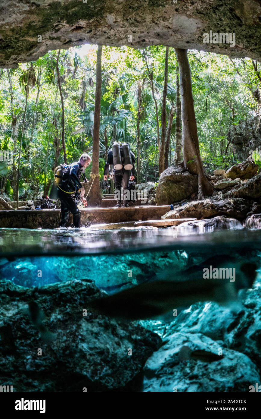 Deux plongeurs quitter Tajma Ha Cenote dans la jungle. Banque D'Images