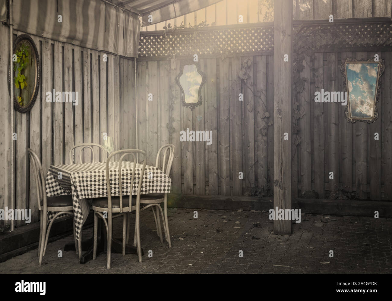 Un bistro, une table et des chaises sur lesquelles tombent les rayons. Des murs en bois, des miroirs anciens et sur les murs. Monochrome. Banque D'Images