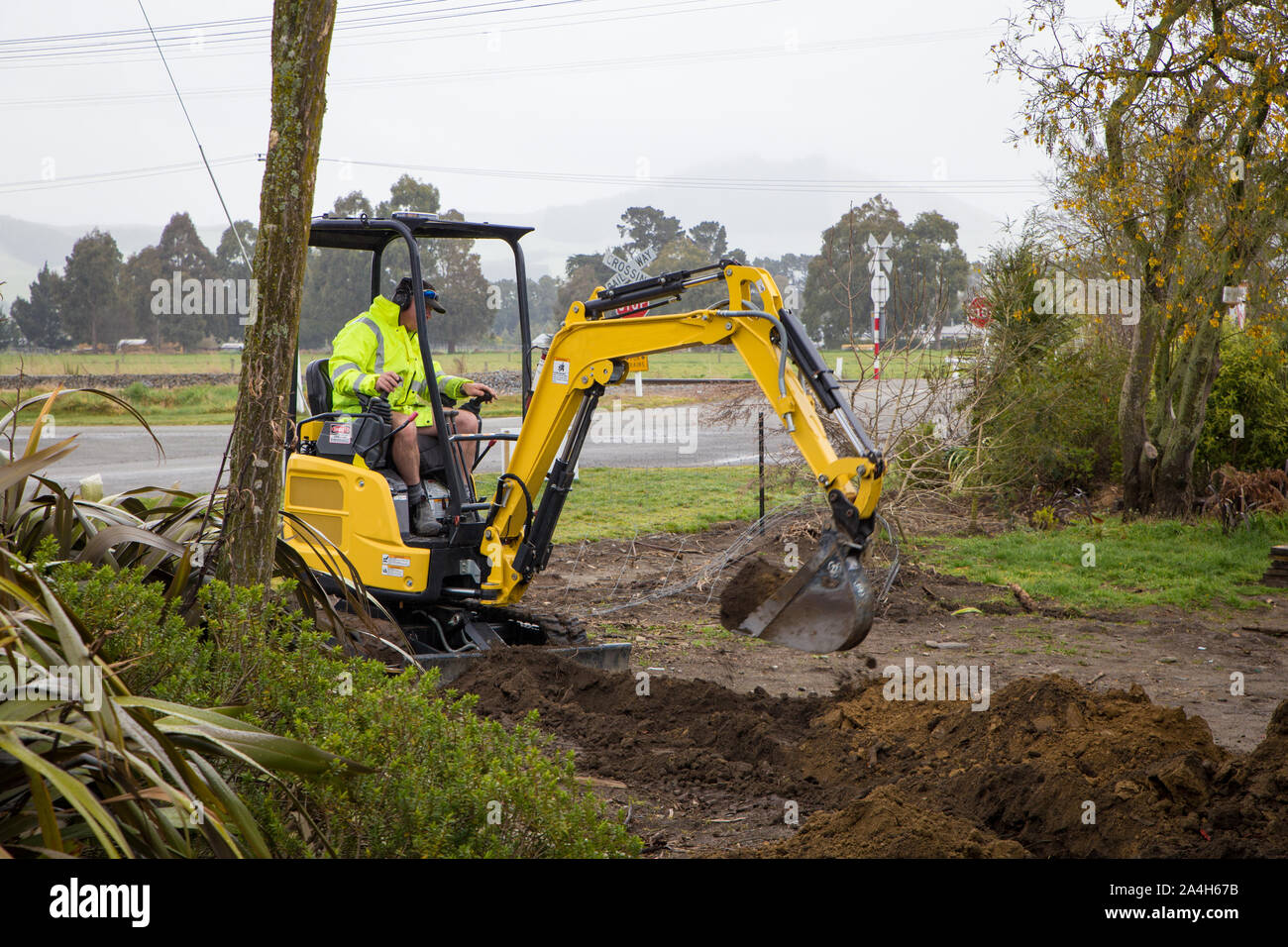 Un constructeur creuse une tranchée sur un chantier pour poser des câbles d'alimentation et de l'eau dans la région de Canterbury, Nouvelle-Zélande Banque D'Images