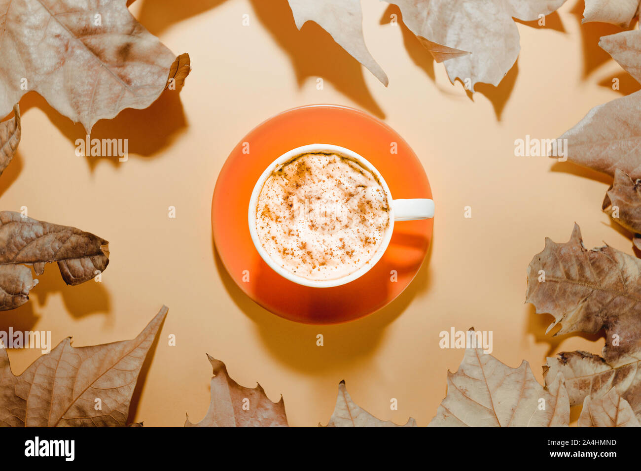 Les feuilles d'automne avec une tasse de café sur fond brun. Mise à plat Banque D'Images