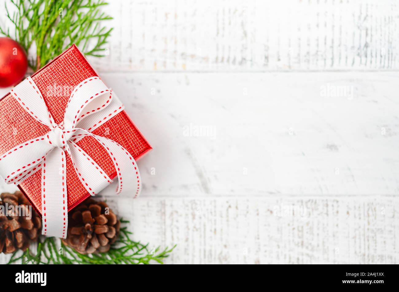 Fond de Noël avec boîte cadeau rouge sur un fond de bois blanc. Concept de fête d'hiver. Banque D'Images