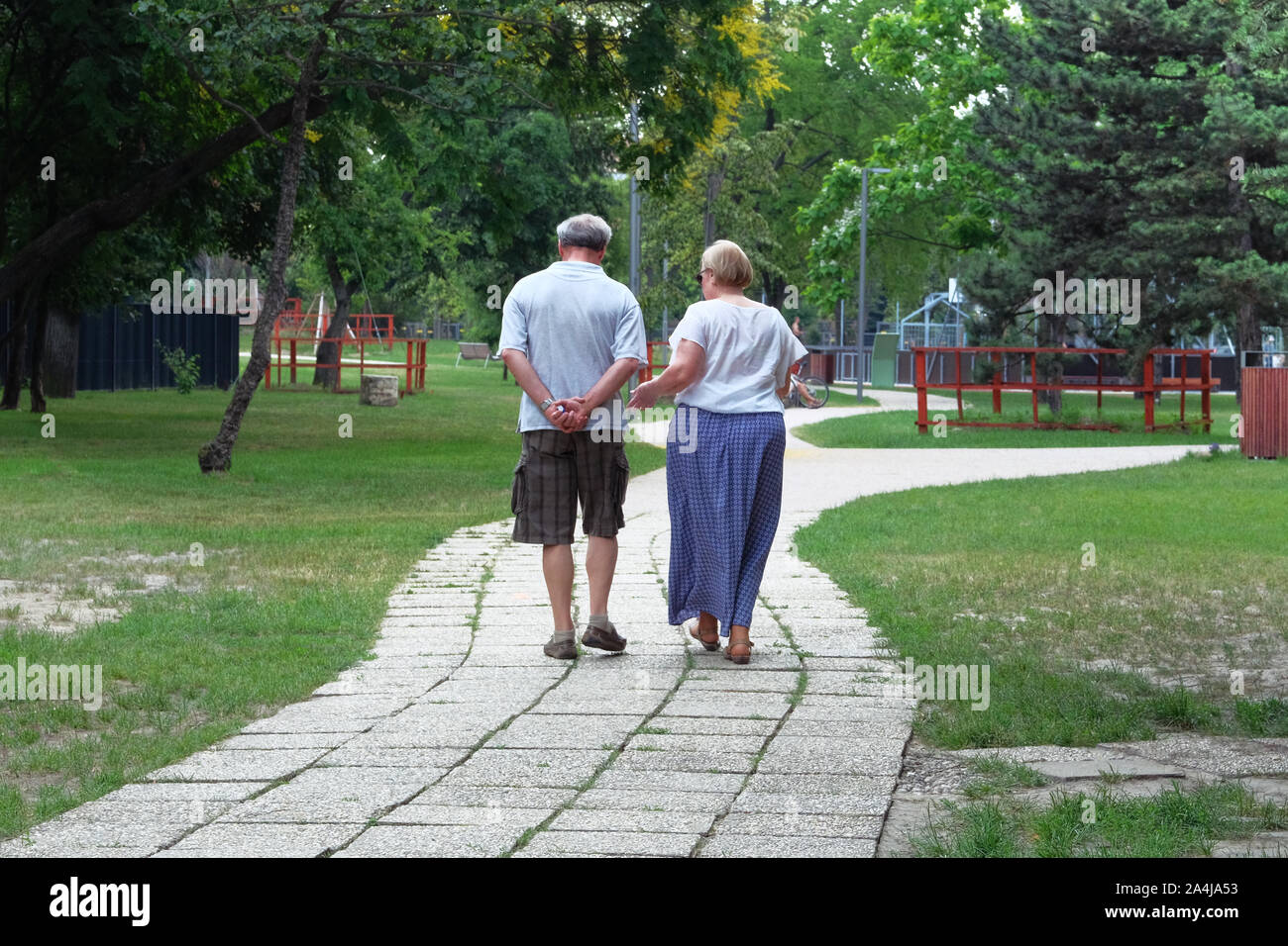Couple d'âge moyen est de marcher dans la forêt. Des arbres sur les côtés du sentier. Vieux couple marche dans Green Park en vacances. Jour d'été ensoleillé. Banque D'Images