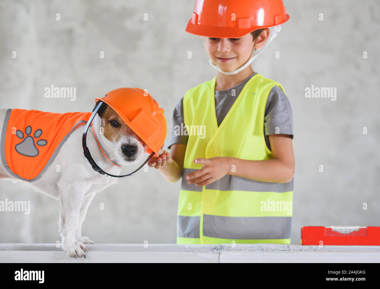 Funny dog wearing hardhat de travers au chantier et à l'enfant dans les vêtements de protection Banque D'Images