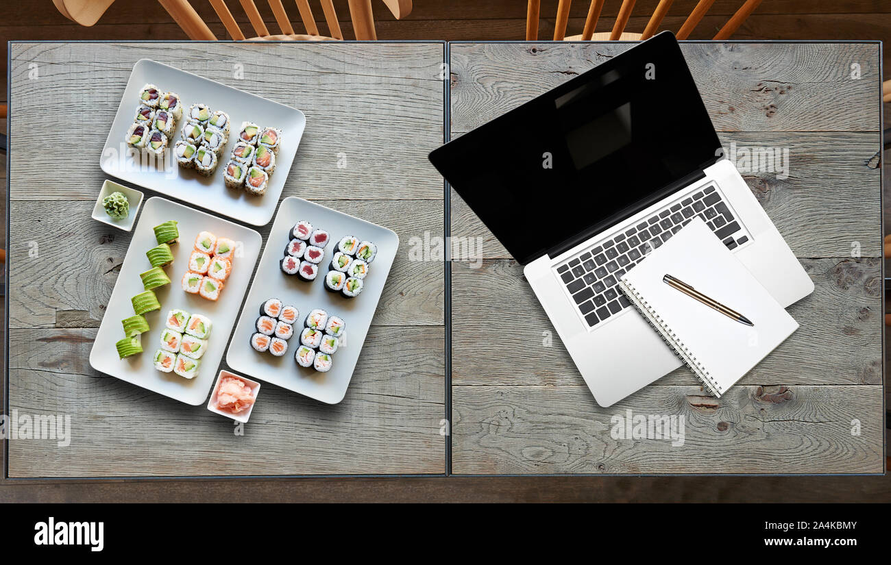Livraison certains assiette de sushis et ordinateur portable sur deux tables en bois Banque D'Images