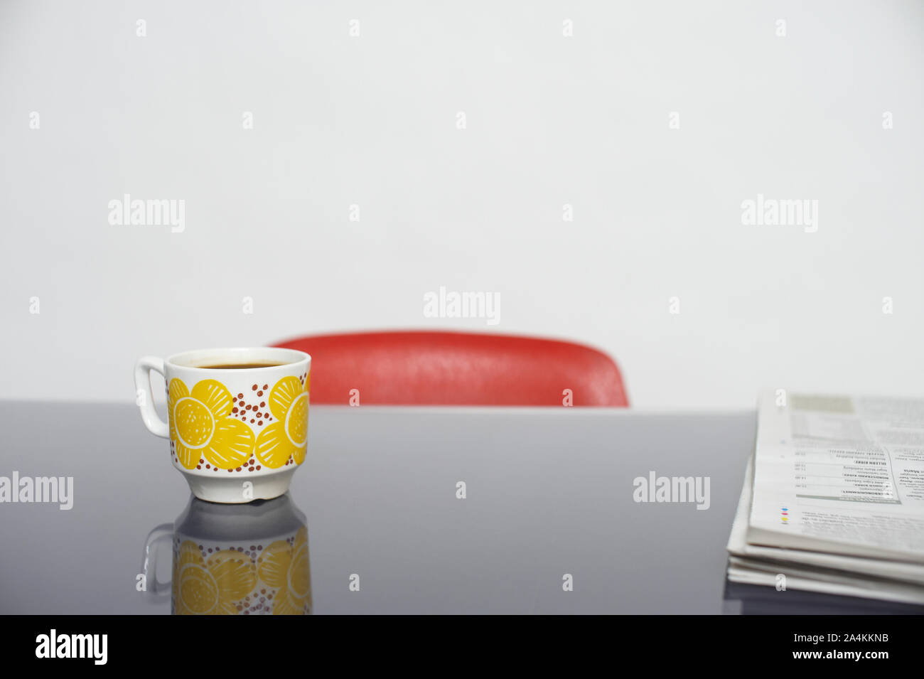 Coupe jaune sur table en verre. Fauteuil rouge Banque D'Images