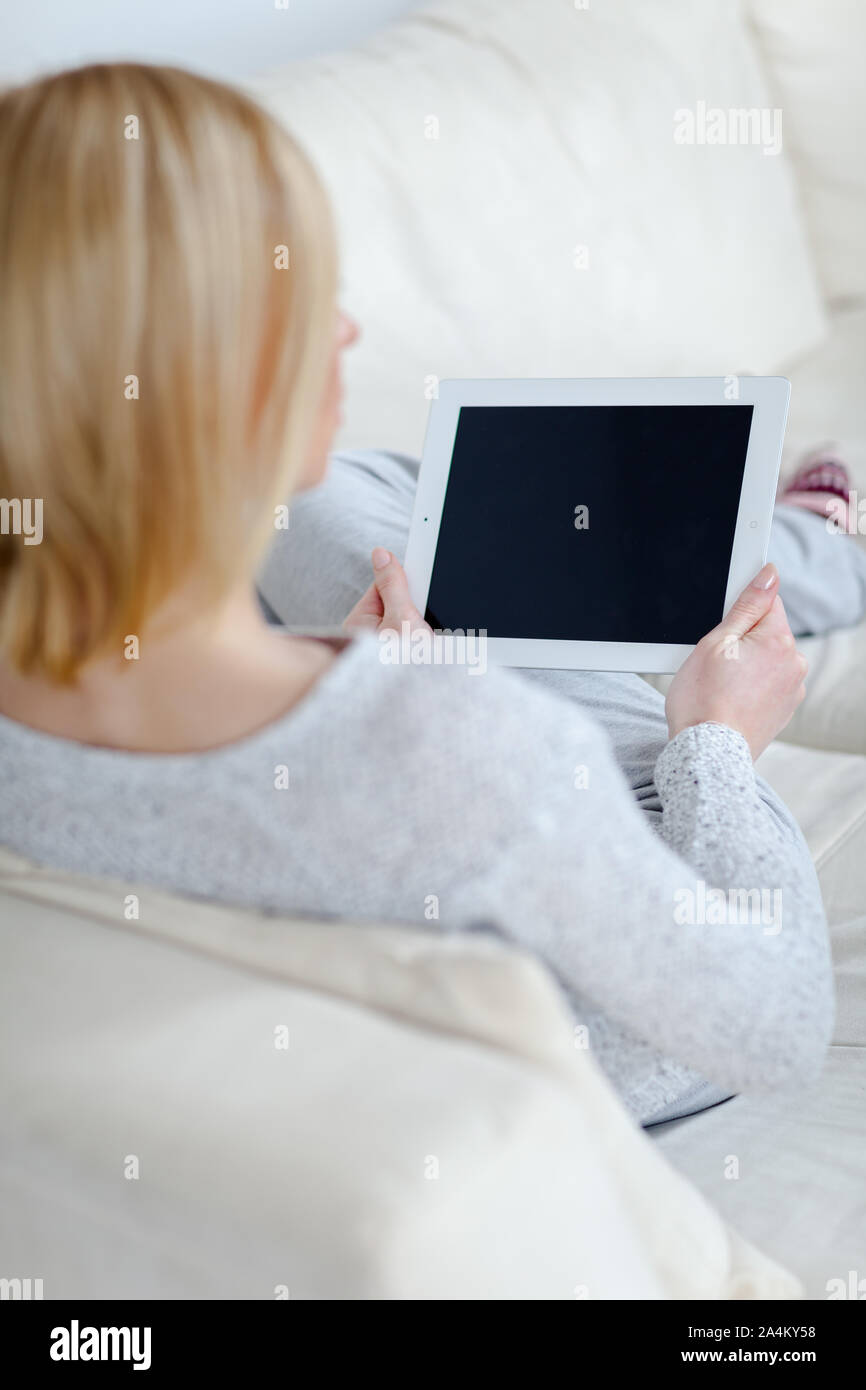 Une femme est en train de lire une tablette sur la table Banque D'Images