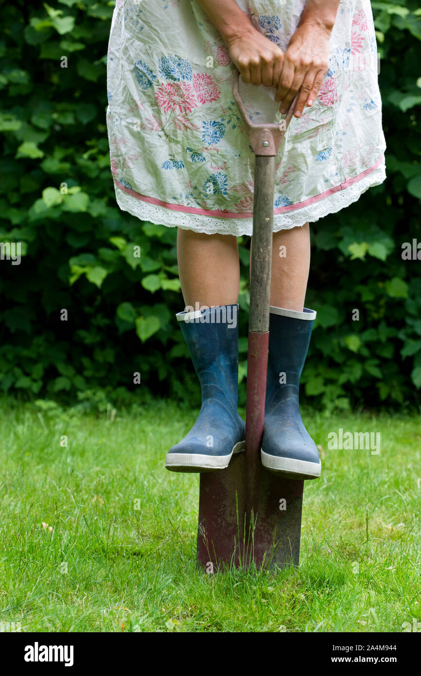 Femme avec une pelle et des bottes en caoutchouc. Banque D'Images