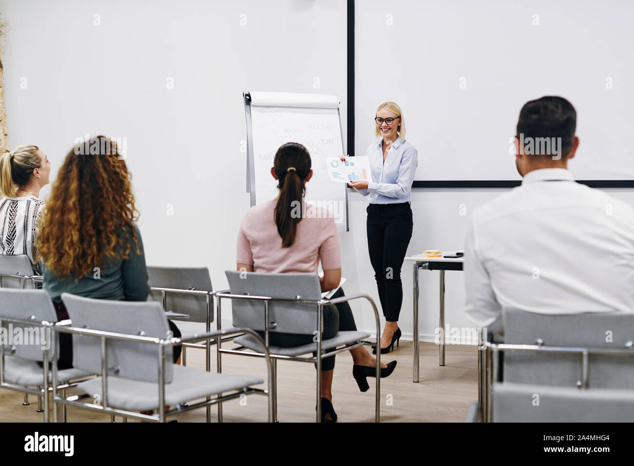 Smiling manager passe plus de graphiques et tableaux au cours d'une présentation au personnel dans une salle de réunion dans un bureau Banque D'Images