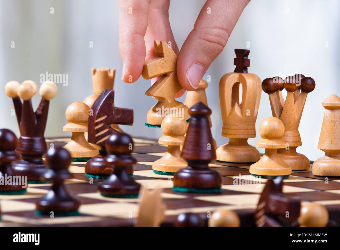 La main de joueur avec le chevalier blanc au cours de partie d'échecs Banque D'Images